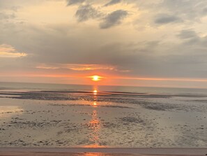 Une plage au coucher du soleil, avec une eau calme et un ciel dégagé.