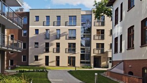 Ein modernes Apartmenthaus mit mehreren Balkonen und einem Innenhof.