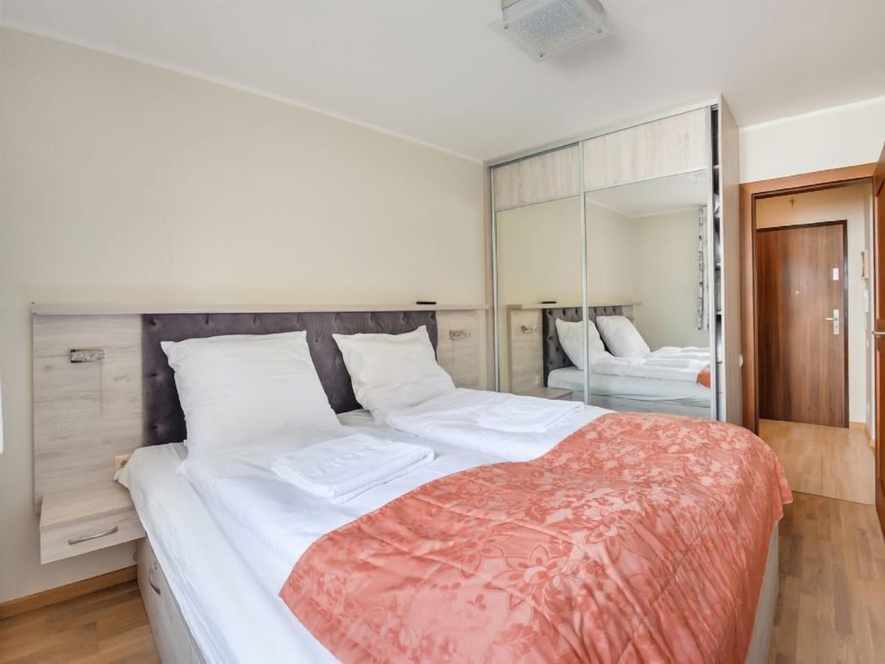 A bedroom with a bed, a wardrobe, and a mirror.
