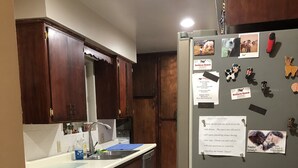 A kitchen with wooden cabinets, a stainless steel sink, and a refrigerator with magnets and notes. - Vacation with the Horses in our Ranch House! Right off Hwy 395 (Inyokern)