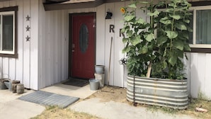 A house with a red door, a large sunflower plant, and a metal barrel planter. - Vacation with the Horses in our Ranch House! Right off Hwy 395 (Inyokern)