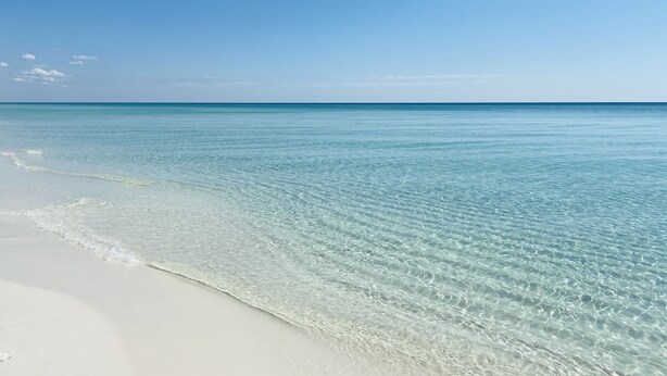 Ein Strand mit klarem türkisfarbenem Wasser und weißem Sand.