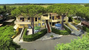 Un edificio amarillo de varios pisos, con terraza y una piscina pequeña.