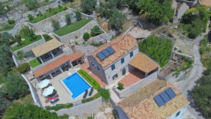 Une propriété résidentielle dotée d’une piscine, de murs en pierre et de panneaux solaires.
