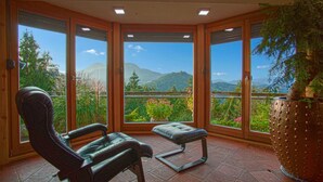 Une pièce avec vue sur les montagnes, une chaise, un banc et une plante en pot.