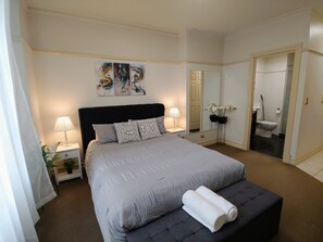 Relax in a spacious room with a large bed, bedside table, and comfortable seating area.