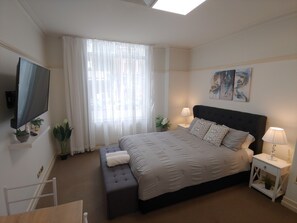 Relax in a spacious room with a large bed, flat-screen TV, and large window.