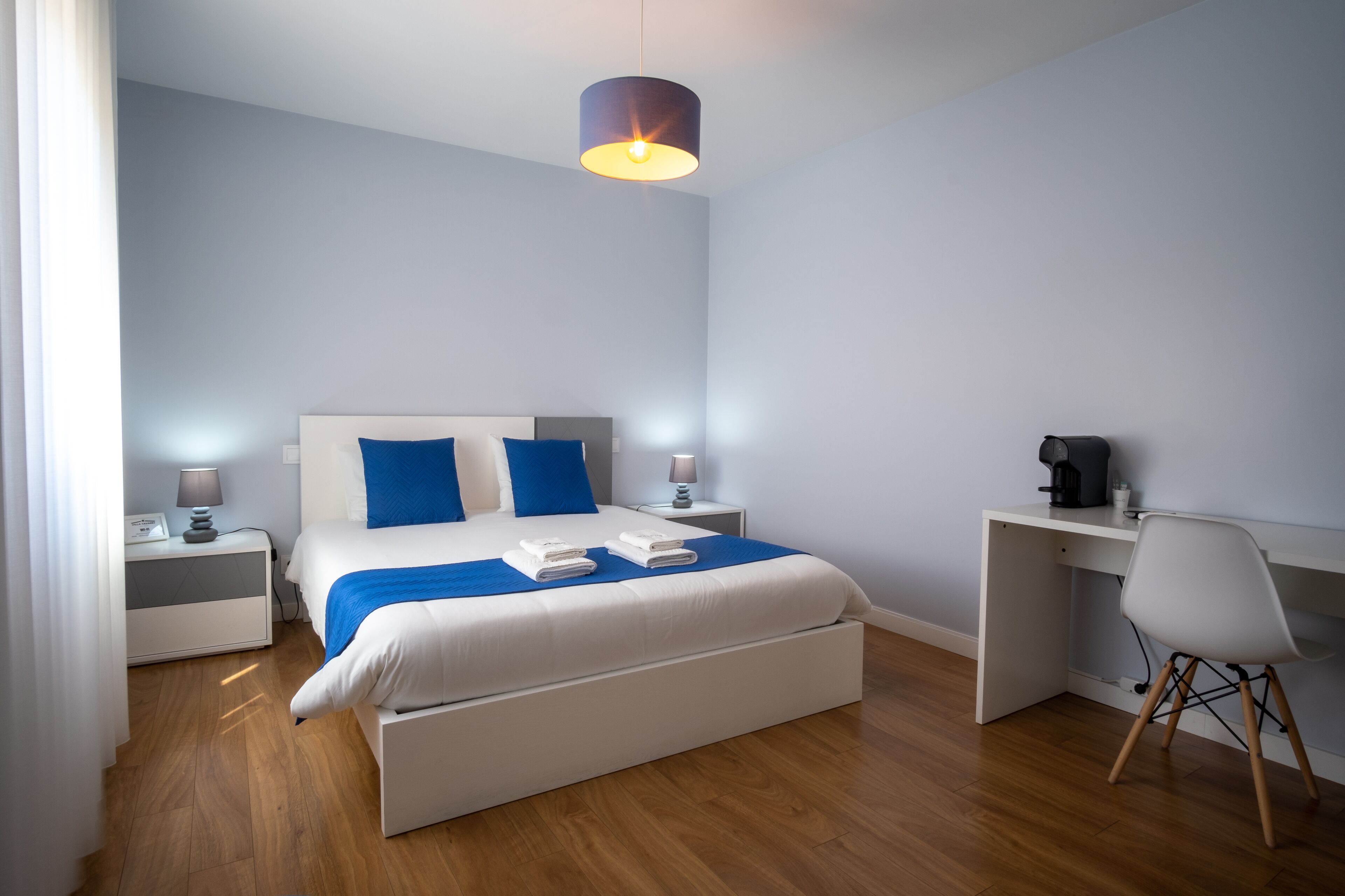 A modern hotel room with a large bed, a desk, and a chair.