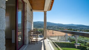 Un balcon donnant sur des collines lointaines, avec une table et des chaises.