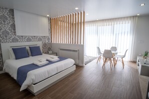 Habitación de hotel moderna con una cama grande, un escritorio y un comedor.