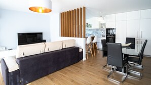 Un salon moderne comprenant un canapé, un téléviseur, une table à manger et des chaises.