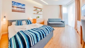 A modern hotel room with a large bed, a chair, a TV, and a painting on the wall.