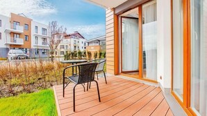 A modern outdoor patio with a wooden deck, a table, and two chairs.