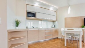 A modern kitchen with wooden cabinets, a built-in microwave, and a dining area with a white table and chairs.