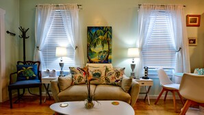 A living room with a sofa, two chairs, a coffee table, and a painting on the wall.