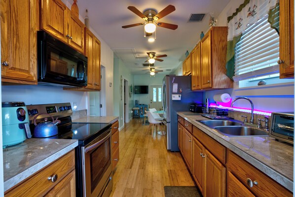 A kitchen with wooden cabinets, a microwave, a refrigerator, and a ceiling fan.