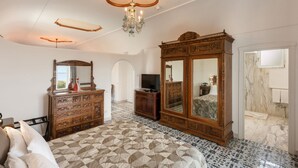 Un dormitorio con una cama grande, un armario de madera, un televisor y una araña.