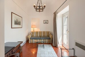 A living room with a sofa, a table, a lamp, and a chandelier.