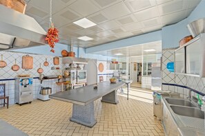 A spacious kitchen with a central island, stainless steel appliances, and copper cookware on the wall.