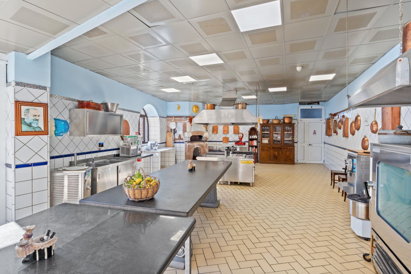 A spacious kitchen with a long counter, stainless steel appliances, and a variety of cooking utensils.