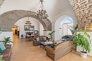 A spacious living area with a high arched stone ceiling, a fireplace, and a dining area with a chandelier.