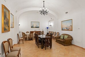 A dining area with a round table and chairs, a sofa, and artwork on the walls.