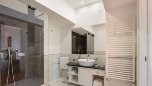Un baño moderno con cabina de ducha de vidrio, un lavabo blanco y un mueble de tocador con espacio de almacenamiento.