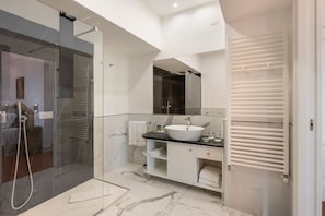 A modern bathroom with a glass shower enclosure, a white sink, and a vanity with storage.