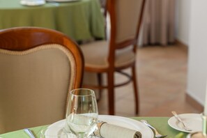 A dining table with a glass, plate, and cutlery, set against a green tablecloth.