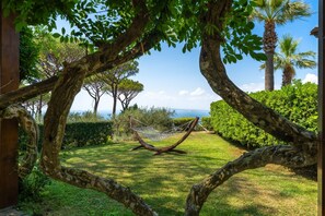 Un'amaca in un giardino rigoglioso con vista sul mare.