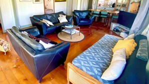 Amplia sala de estar con un conjunto de sofás, una mesa de comedor y una cocina visible a través de un arco.