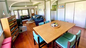 Un amplio salón con una mesa de comedor de madera, sillas azules, un sofá y una estantería.
