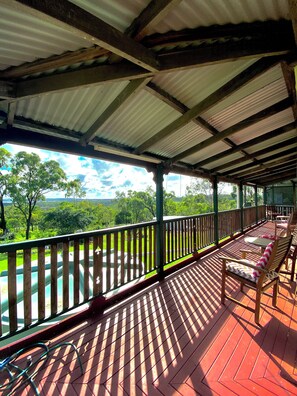 A covered outdoor deck with wooden railings and chairs, overlooking a lush green landscape. - Escape2Fish - Purpose built fishing base for Boats, Crews & Early Starts (Rodds Bay)