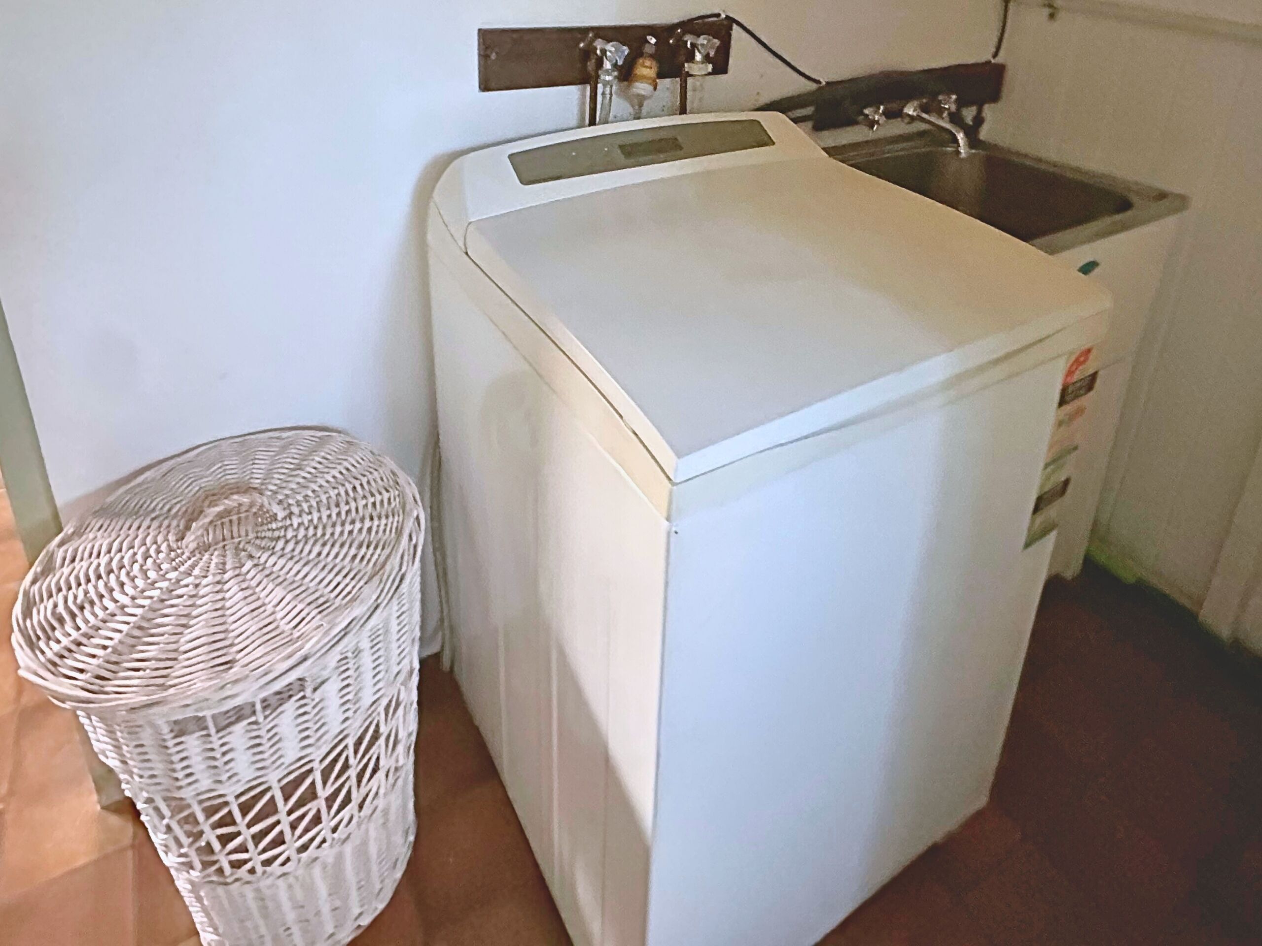 Una lavatrice bianca compatta con un pannello di controllo e un piccolo lavandino.