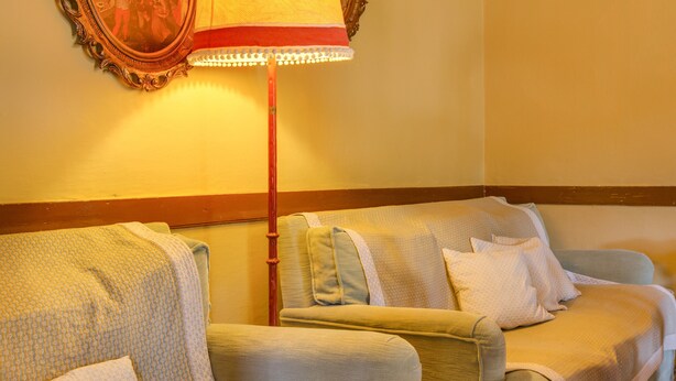 A room with two armchairs, a floor lamp, and a mirror on the wall.