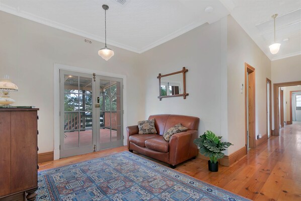 A spacious living room with a brown leather sofa, a patterned rug, and a potted plant.