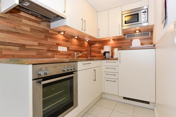 A compact kitchen with a built-in oven, a microwave, and white cabinetry.