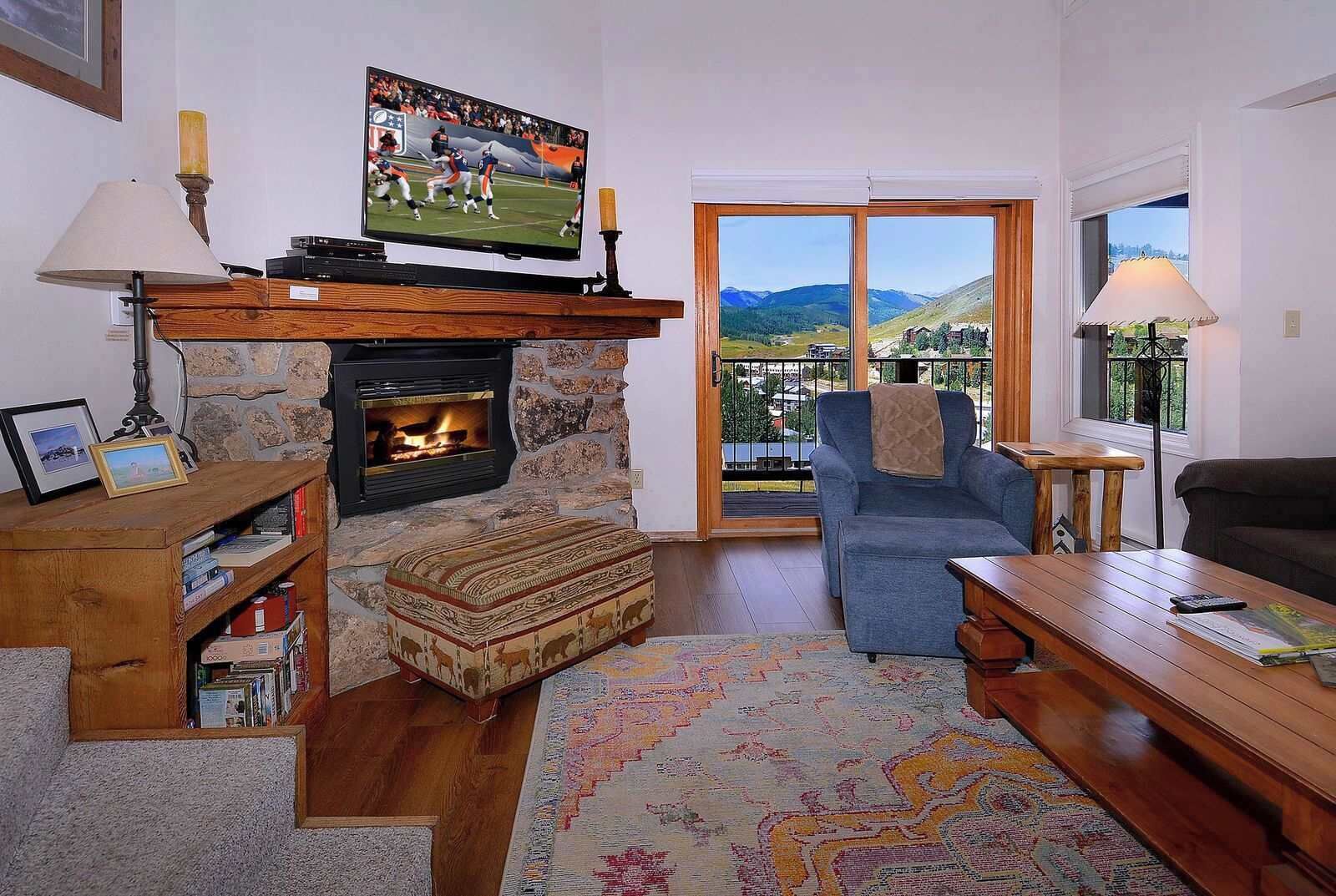 A living room with a fireplace, a television, a sofa, and a view of the outdoors.