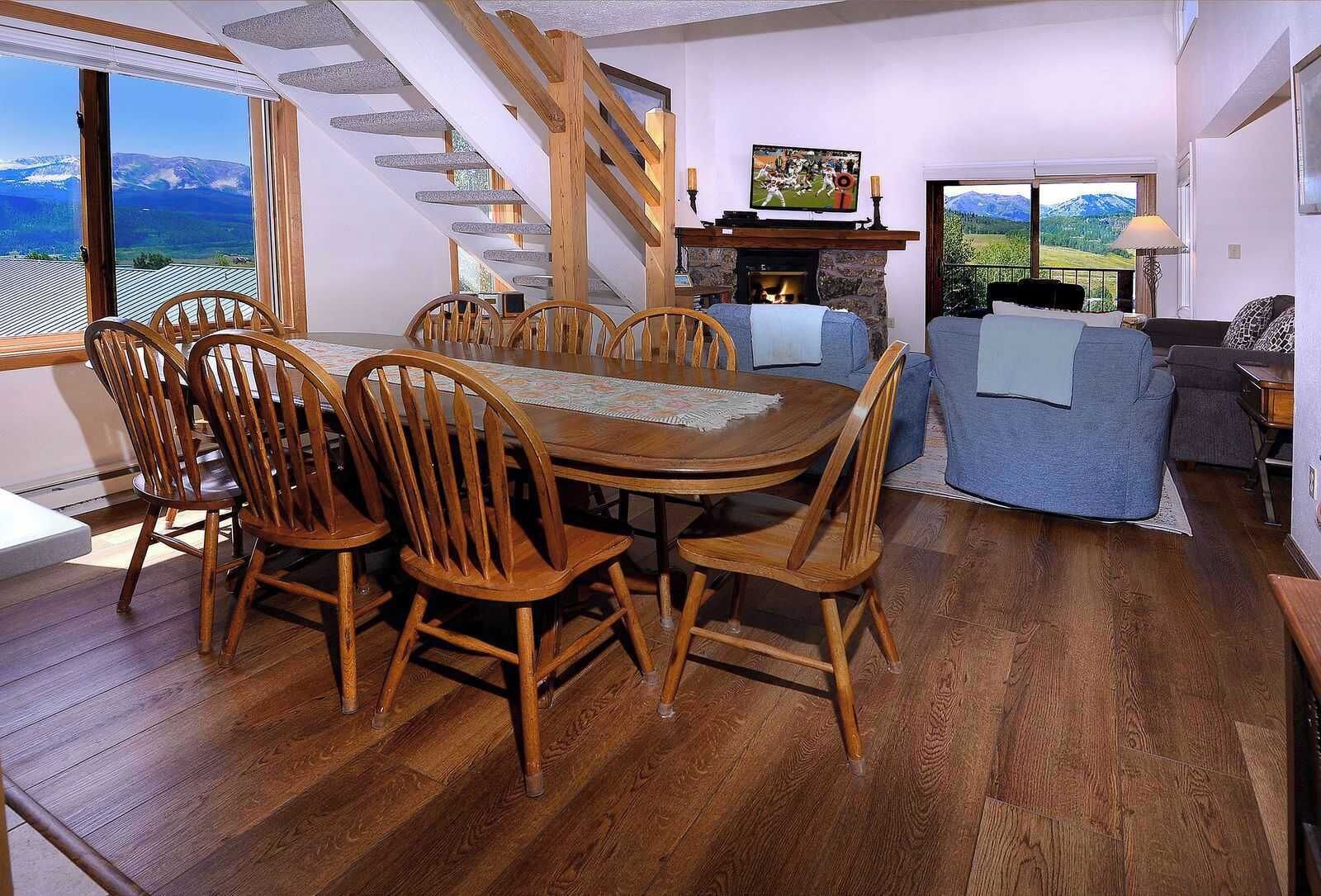 A dining area with a wooden table and chairs, a fireplace, and a television.