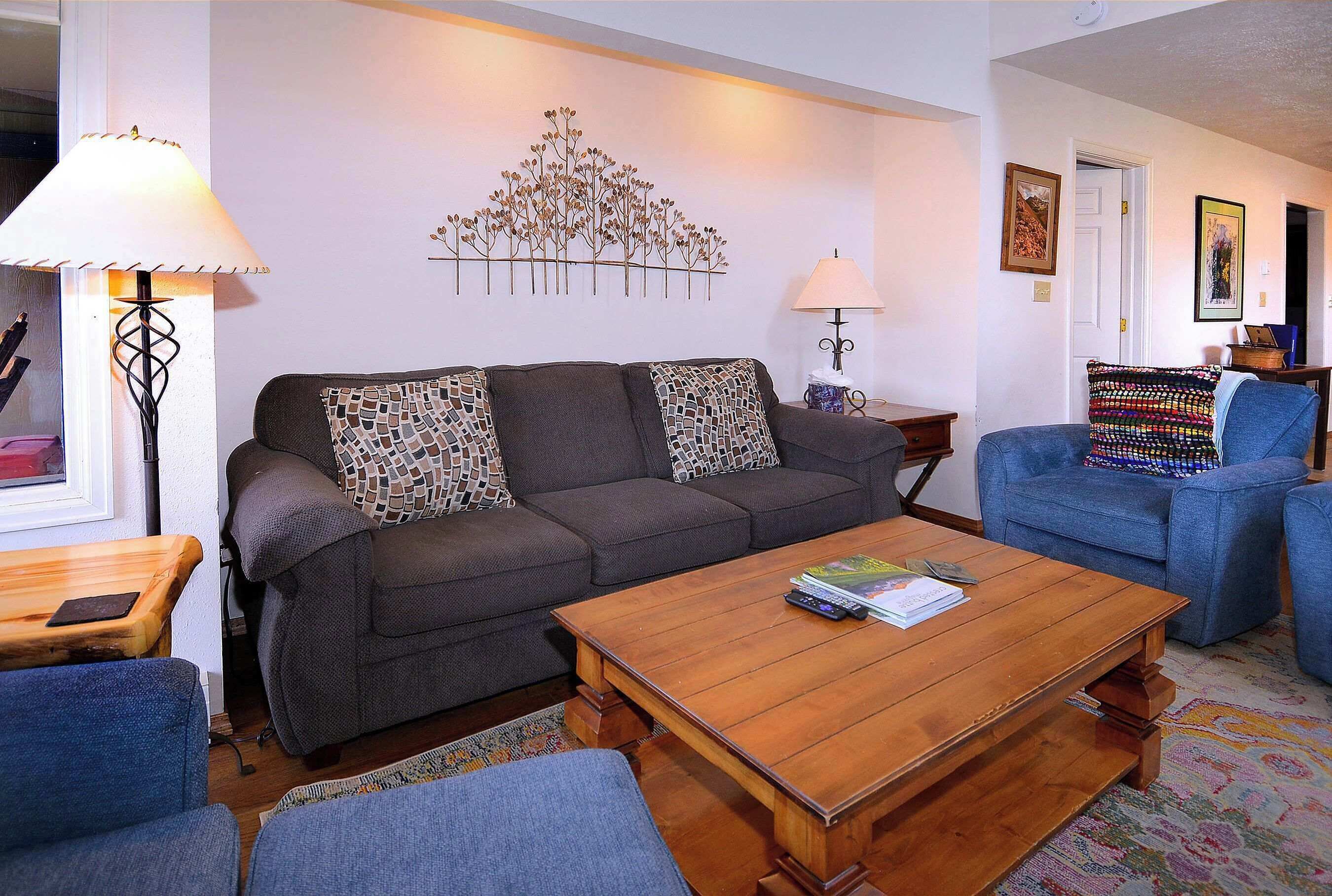 A living room with a sofa, two armchairs, a coffee table, and decorative wall art.