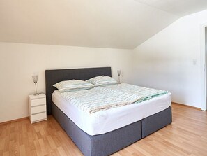 A bedroom with a bed, bedside tables, and a wooden floor.