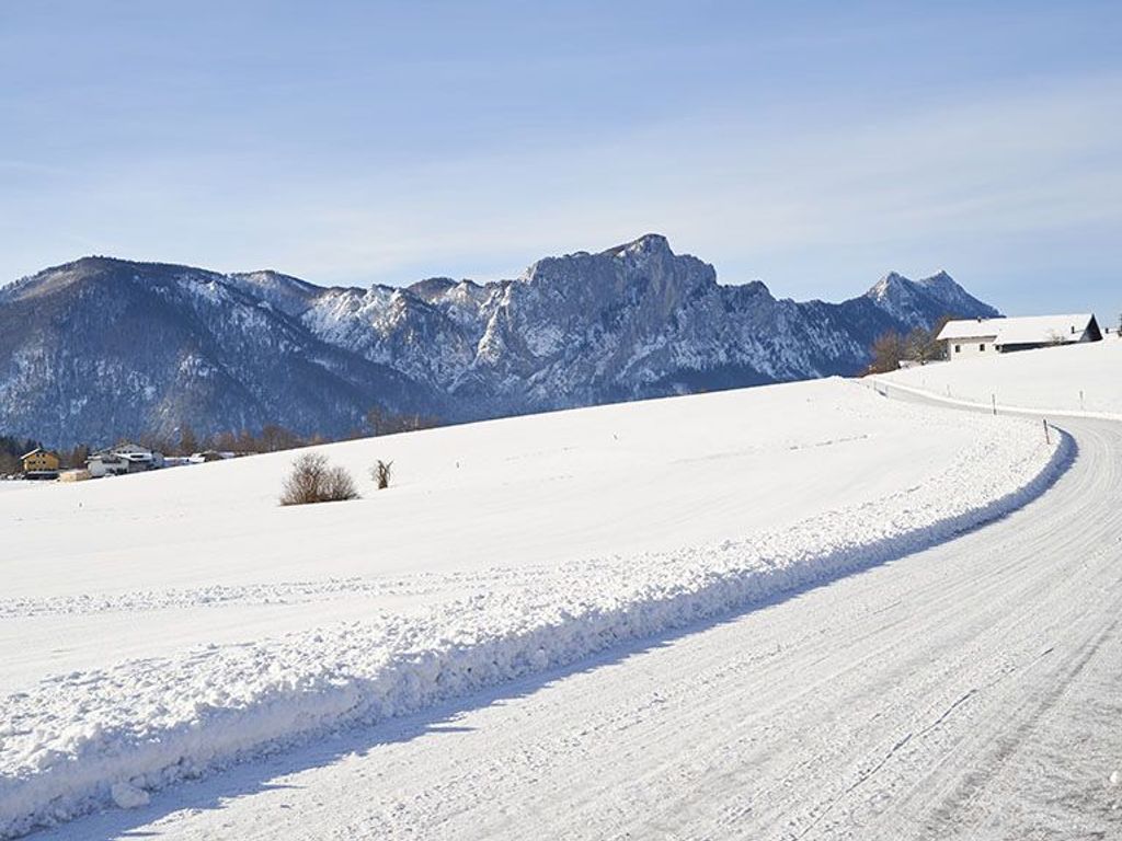 A snow-covered landscape with a mountain range in the background and a clear sky.