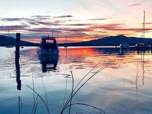 A calm lake with boats at a dock, surrounded by hills.