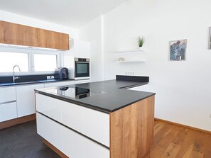 A modern kitchen with a central island, white cabinetry, and a wooden accent wall.