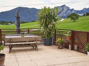 A patio with a wooden bench, potted plants, and a view of mountains. - Bergblick Acht, Österreich (Innerschwand am Mondsee)