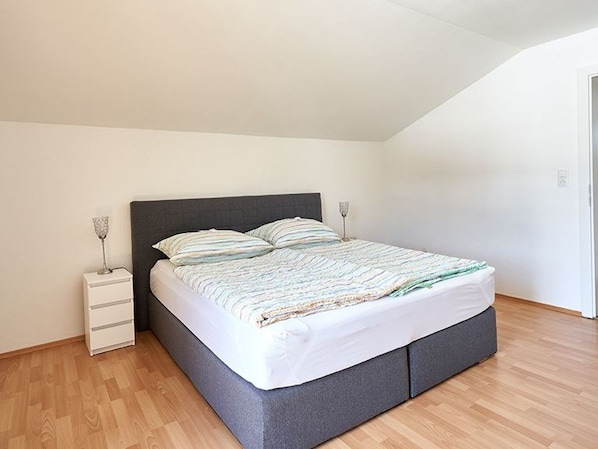 A bedroom with a bed, bedside tables, and a wooden floor.