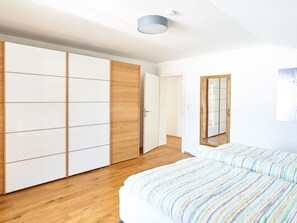 A bedroom with a bed, a wardrobe, a mirror, and a door leading to another room. - Bergblick Acht, Österreich (Innerschwand am Mondsee)
