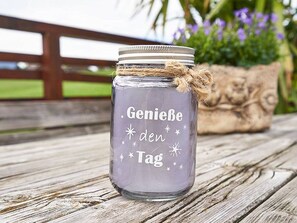 A clear glass jar with a metal lid, tied with twine, and a message on it.