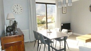Un comedor con una mesa y sillas, un reloj en la pared y vistas al exterior.