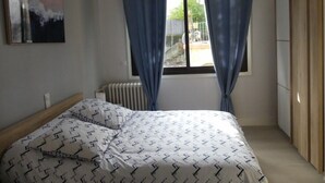 Un dormitorio con cama, un radiador, una ventana con cortinas y un cuadro en la pared.